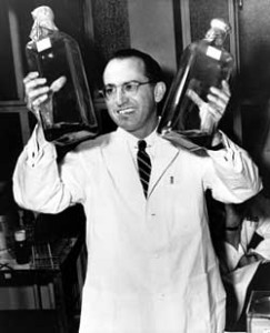 Jonas Salk in 1955 holds two bottles of a culture used to grow polio vaccines.